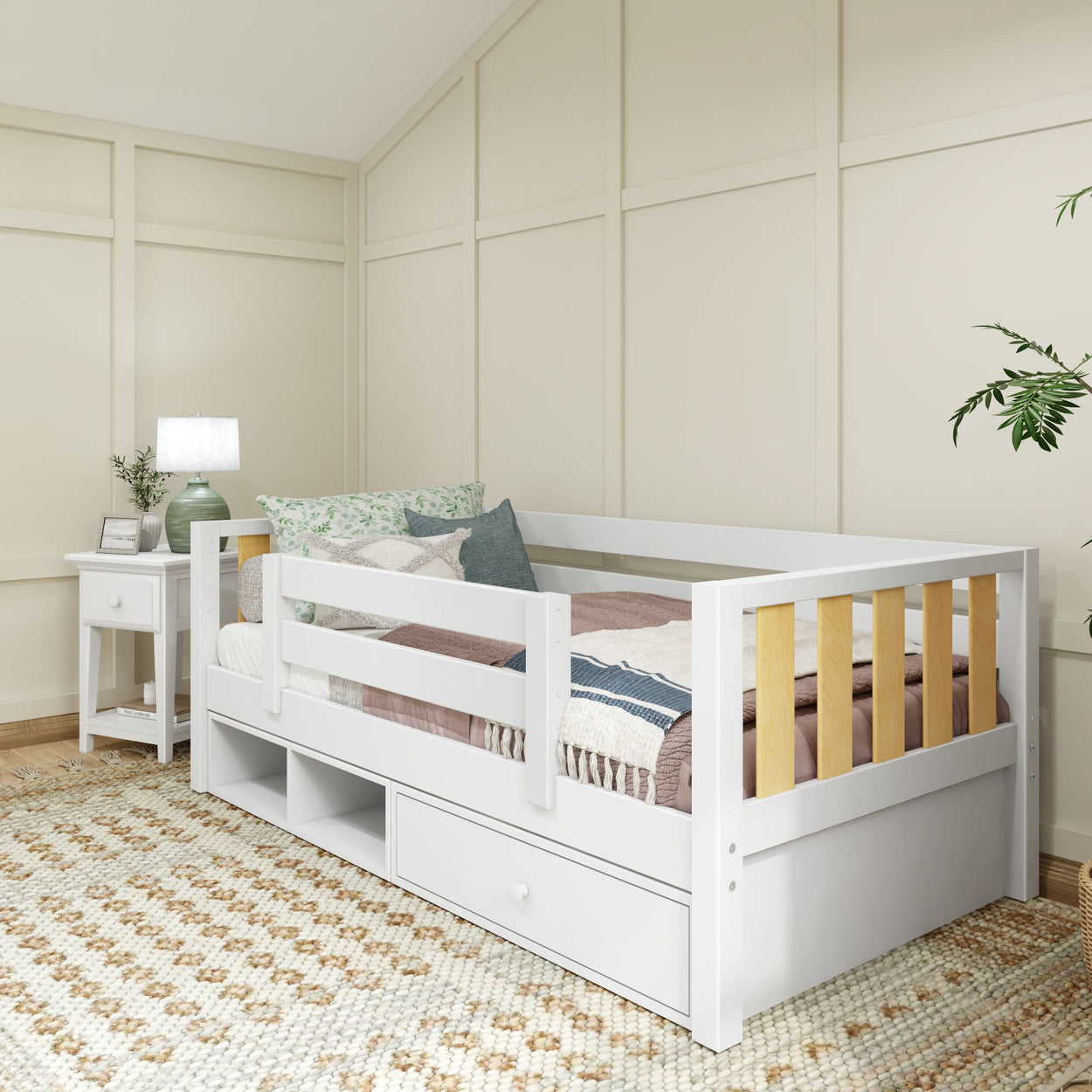White toddler bed with storage drawers and safety rails in a cozy bedroom setting.