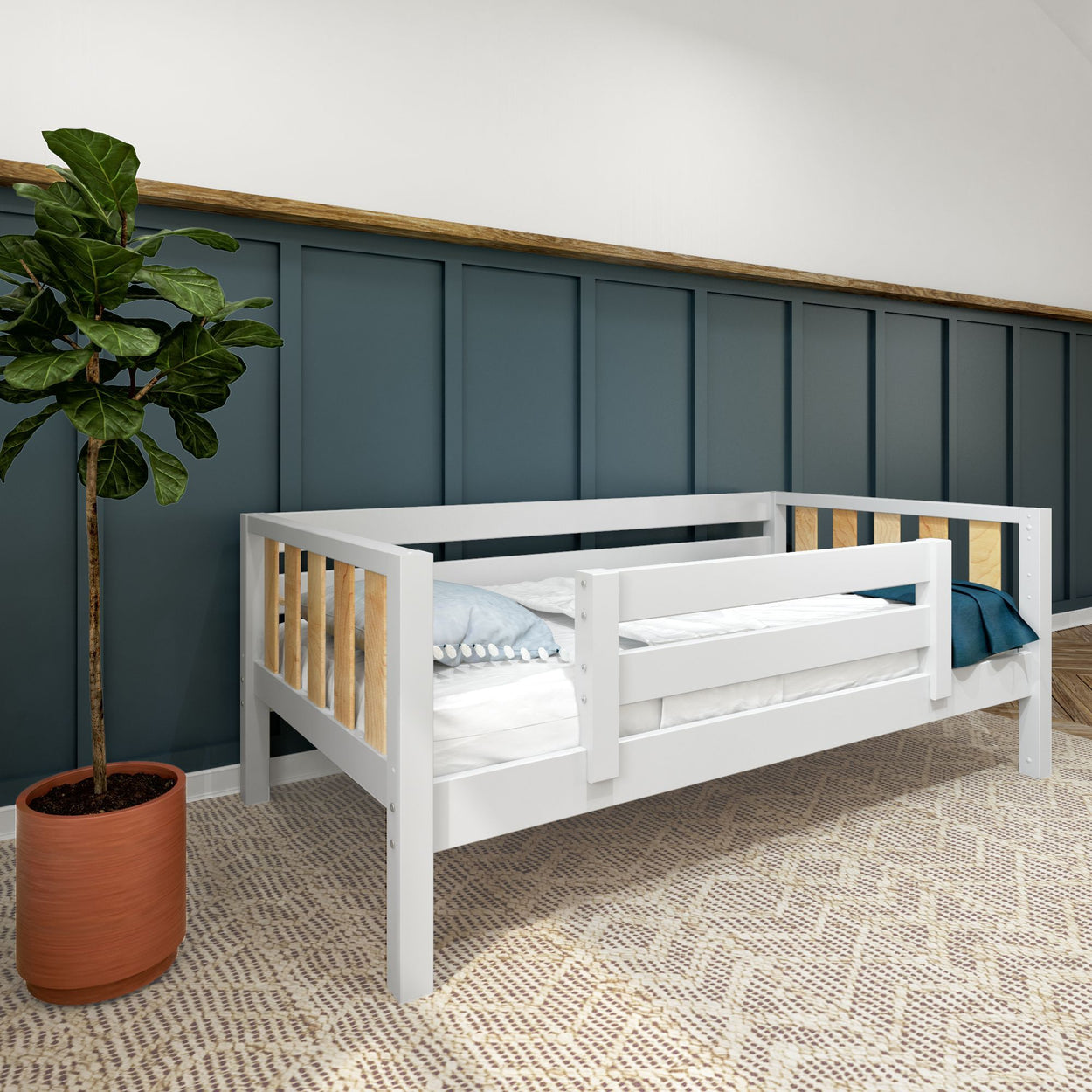 Modern white toddler daybed with safety rail in a stylish room, featuring a potted plant and textured rug.
