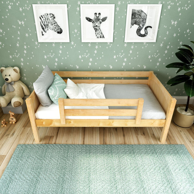 Wooden toddler bed in mint-green nursery with star wallpaper, animal framed prints, teddy bear and textured rug — kids bedroom decor