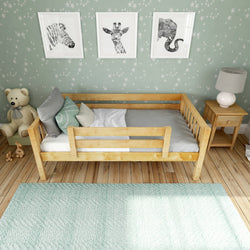 Light wooden toddler bed in cozy kids bedroom with green star wallpaper, framed animal wall art, plush teddy, bedside table and mint rug — nursery decor