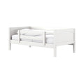 White wooden toddler bed with safety guardrail, paneled headboard and white bedding