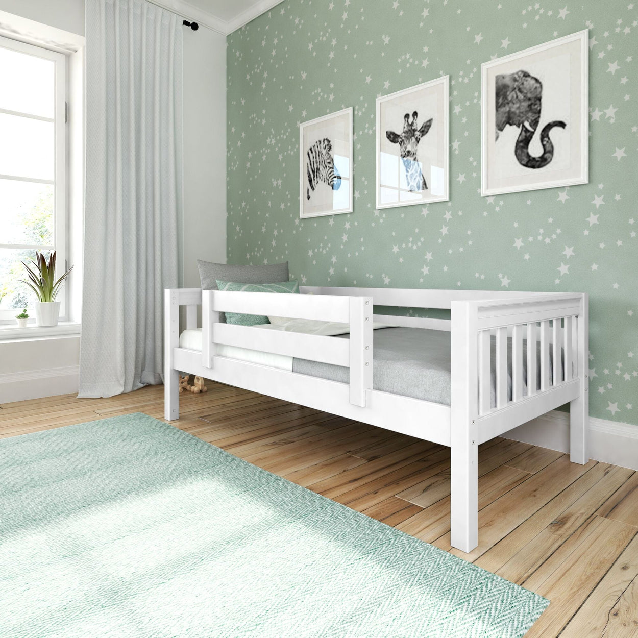 Modern nursery with white wooden crib/toddler bed, mint-green star wallpaper, framed zebra/giraffe/elephant prints, teal rug, sheer curtains and potted plant