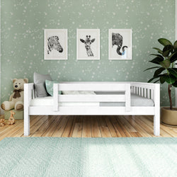Nursery wall decor: mint green star wallpaper with white toddler bed, framed zebra, giraffe and elephant prints, plush teddy bear and potted plant