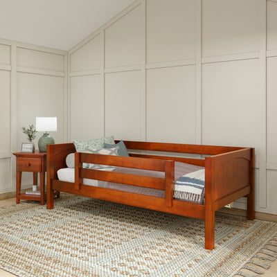 Wooden daybed with railings and side table in cozy bedroom setting, featuring neutral decor and a textured rug.