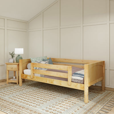 Wooden toddler bed with safety rails in cozy bedroom setting.