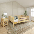 Natural wood toddler bed in cozy nursery with neutral board-and-batten accent wall, woven textured rug, wooden nightstand, lamp, curtains and potted plant