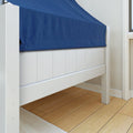 Close-up of white wooden bed frame with blue fitted sheet on light hardwood floor in modern bedroom