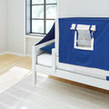 White wooden toddler bed with blue play-tent canopy and clear window panel in a bright modern children's bedroom with light wood floors